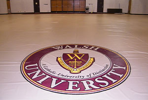 Gym floor cover featuring the Walsh University logo.